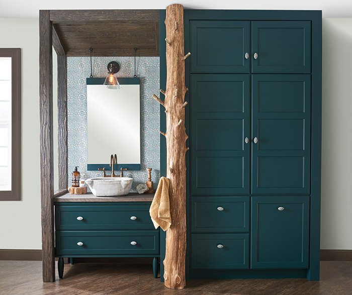 Teal green bathroom vanity and storage cabinets with a tree trunk towel rack