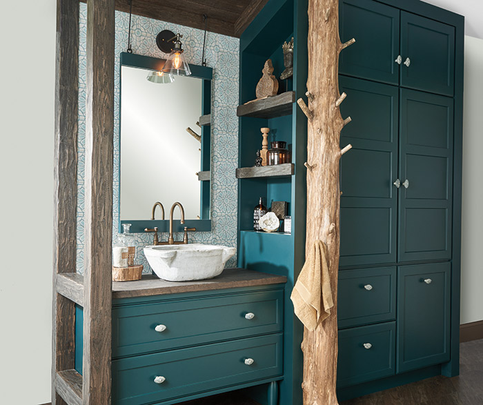 Teal green bathroom vanity and storage cabinets with a tree trunk towel rack